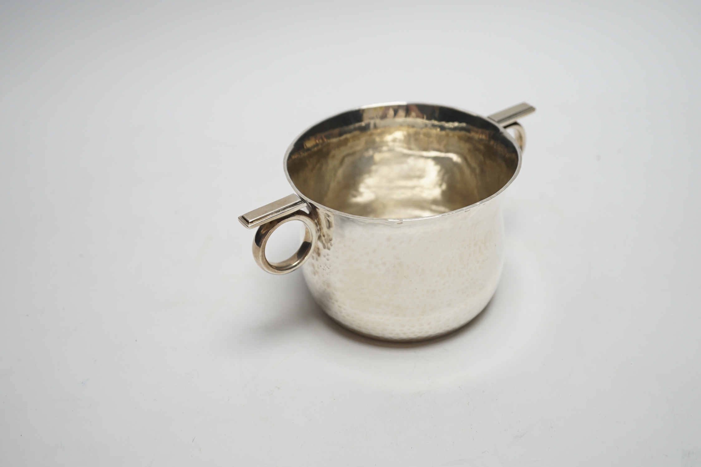 A late Victorian Arts & Crafts planished silver ring handled cup, Goldsmiths & Silversmiths Co Ltd, London, 1900, height 75mm, 8.8oz.